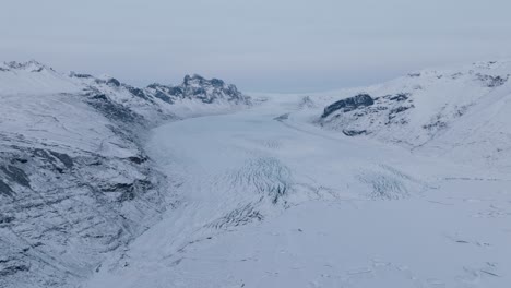 Aerial-panoramic-landscape-view-over-Skaftafellsjokull-glacier-in-Iceland,-covered-in-snow,-at-sunset