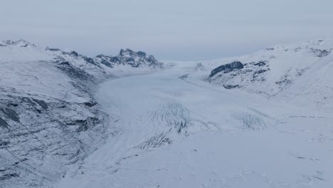 Vista-Panorámica-Aérea-Del-Paisaje-Sobre-El-Glaciar-Skaftafellsjokull-En-Islandia,-Cubierto-De-Nieve,-Al-Atardecer