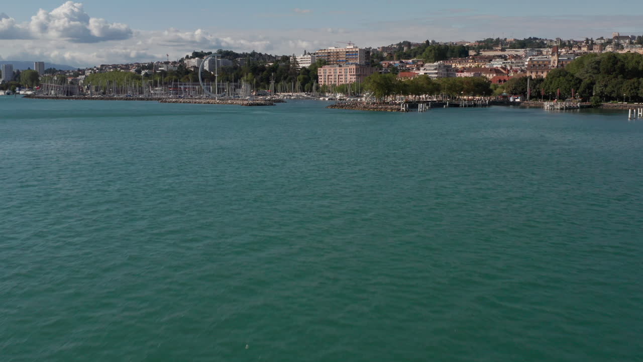 아름다운 푸른 호수의 공중과 도시 가장자리에 있는 요트 항구를 드러내기 위해 위로 기울이기