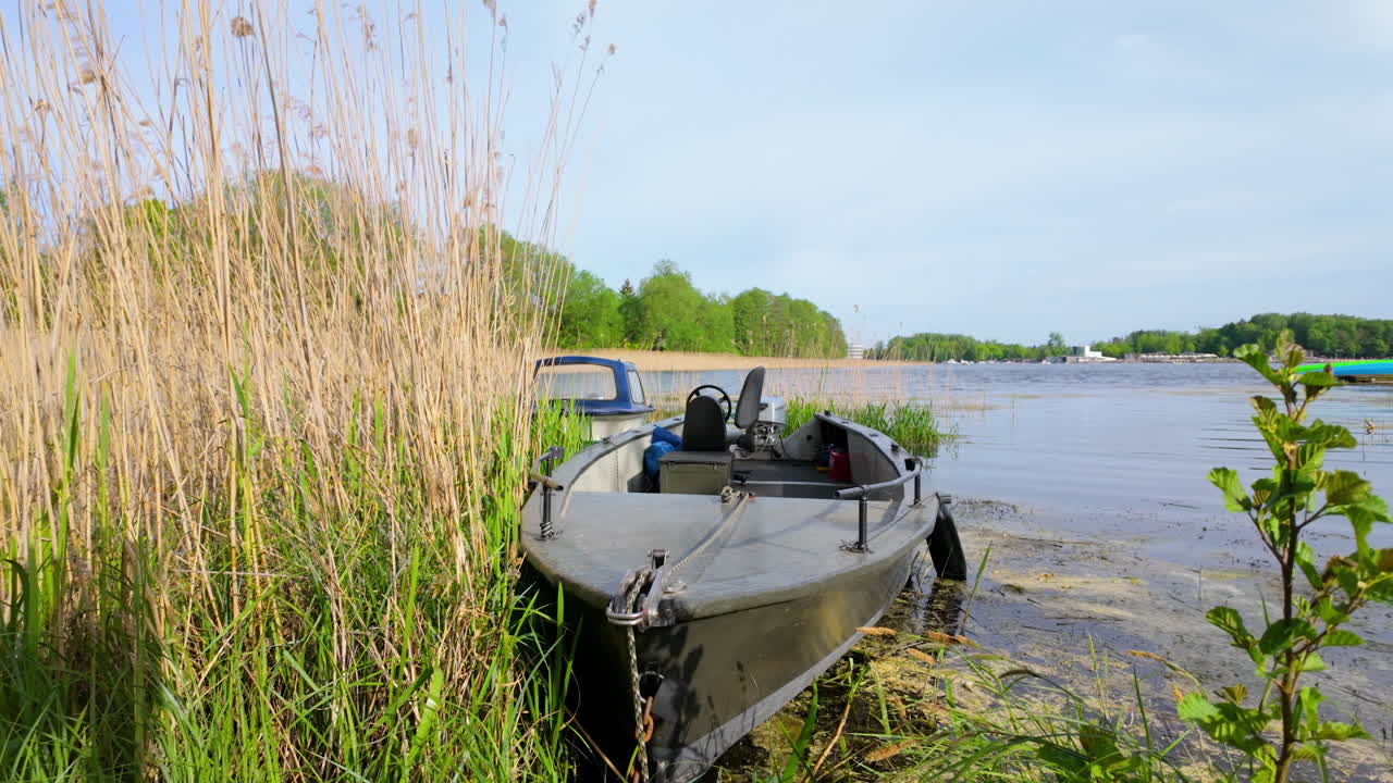 A small boat moored among tall reeds at the edge of Ukiel Lake in Olsztyn, with a calm water surface and trees in the background