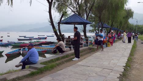 people at the waterfront enjoying the phewa lake in pokhara, nepal