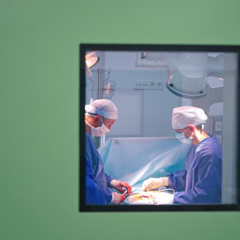 group of surgeons performing an operation. doctors in blue medical uniform in the operating room. view through the window.