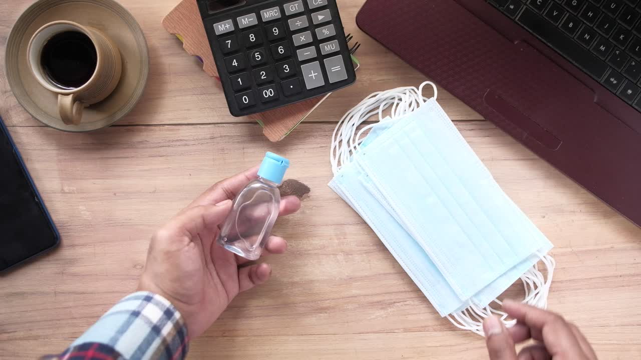 desinfectante para las manos y máscaras faciales en un escritorio de madera