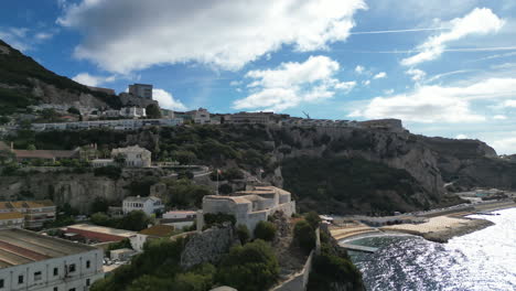 a beautiful 4k drone shot orbiting around parson's lodge with the bay of gibraltar included and the rock of gibraltar on a partly cloudy day