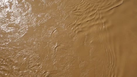 top view of strong current of muddy and turbulent river flowing down