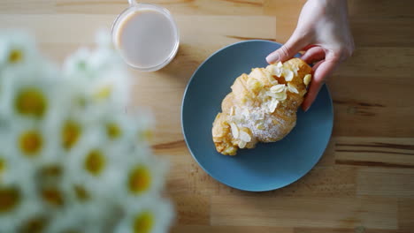 Französisches-Croissant-Mit-Mandelblättchen.-Nahaufnahme-Einer-Frau,-Die-Ein-Croissant-In-Der-Hand-Nimmt