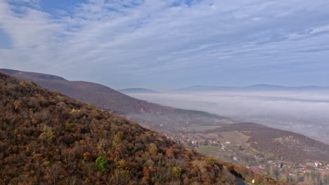 autumn mountain landscape with foggy valley and village
