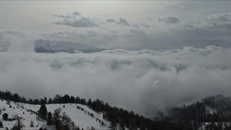 Vista-Aérea-Sobre-Una-Cadena-Montañosa-De-Bosque-Invernal-Con-Nubes-Bajas-Que-Cubren-El-Paisaje-Escénico