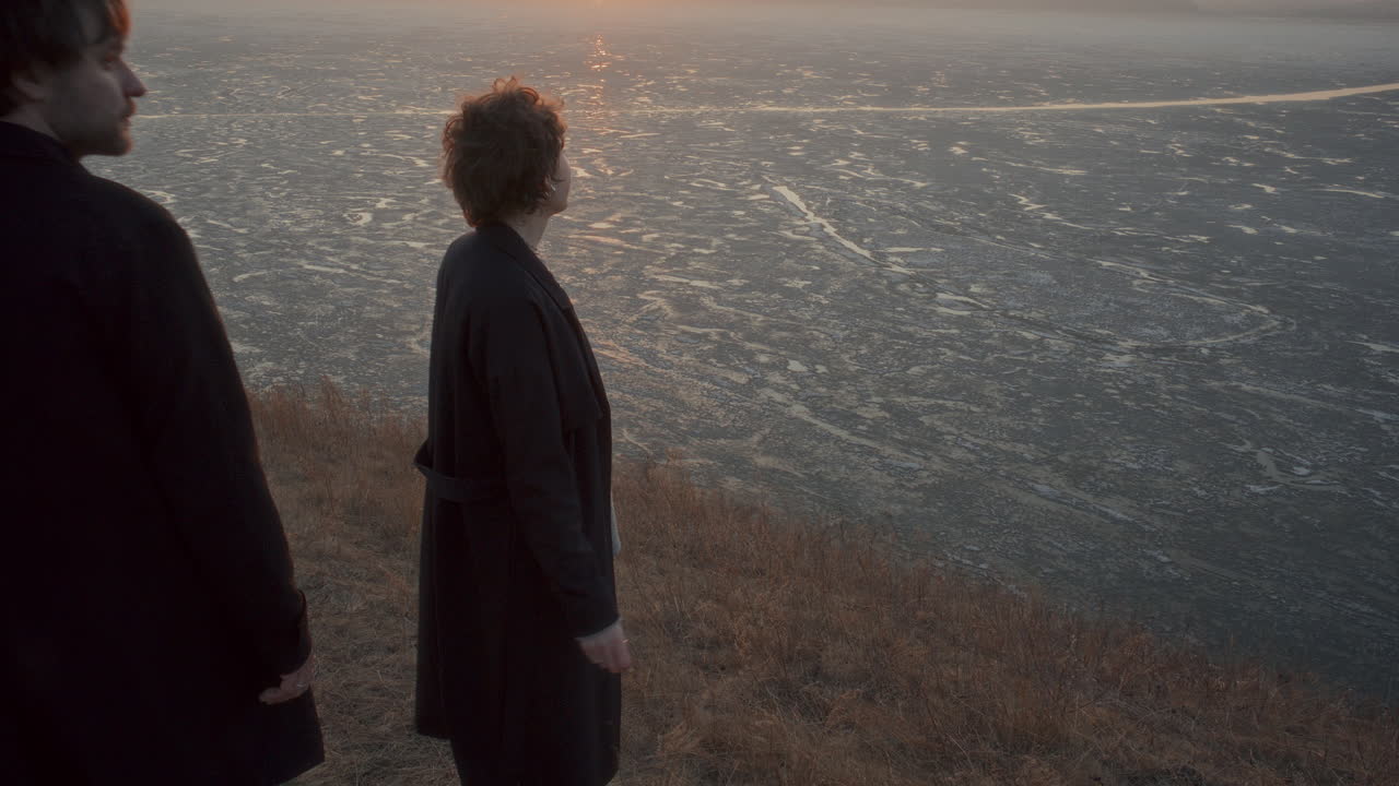 Woman Smoking Cigarette and Talking to Boyfriend on Frozen Lake Shore