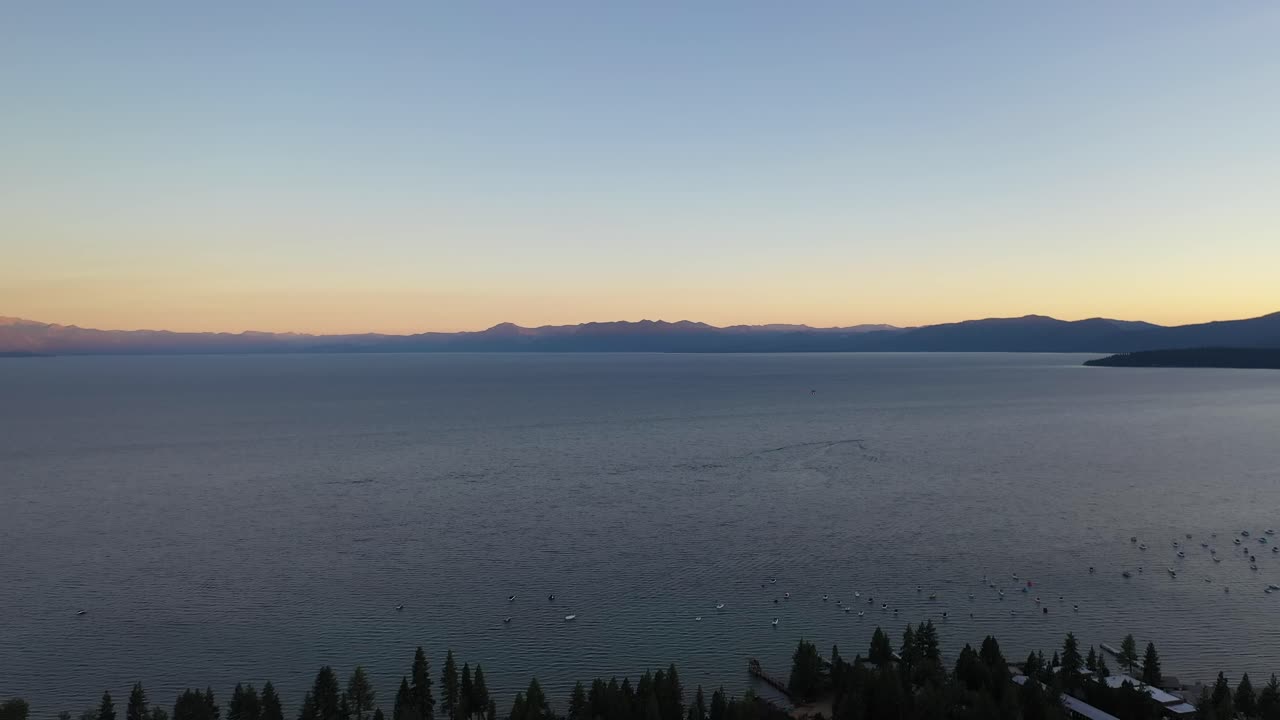 aguas tranquilas del lago tahoe con barcos de vela durante la puesta de sol en california, estados unidos