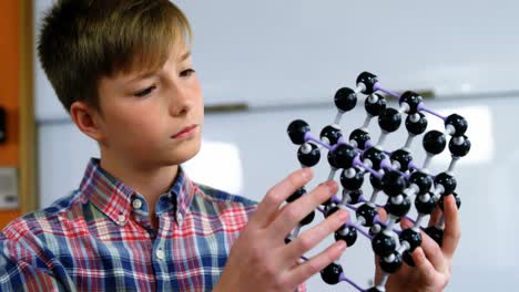 Schoolboy-experimenting-molecule-model-in-laboratory-at-school