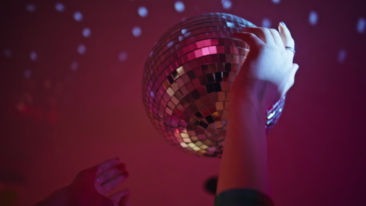 Hands touching disco ball sparkles with reflected light closeup. Female clubber