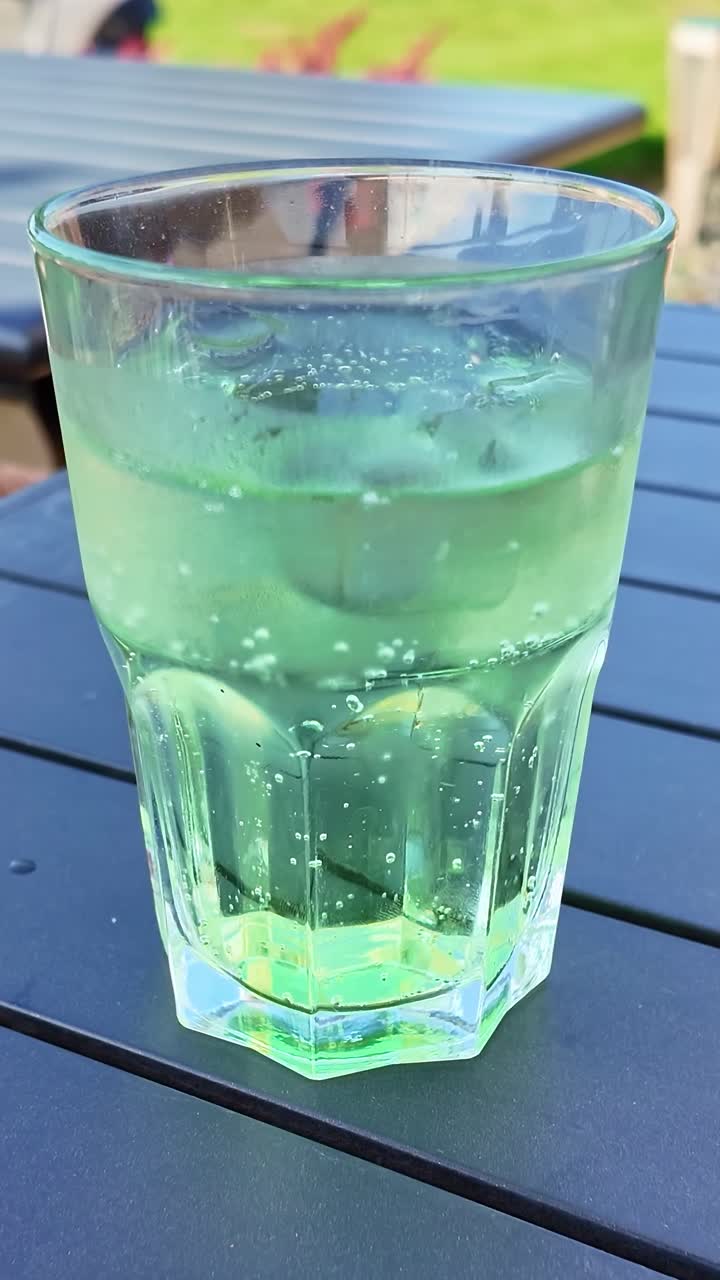 Vertical view about a glass of Diabolo banana kiwi drink with ice on outdoor café table