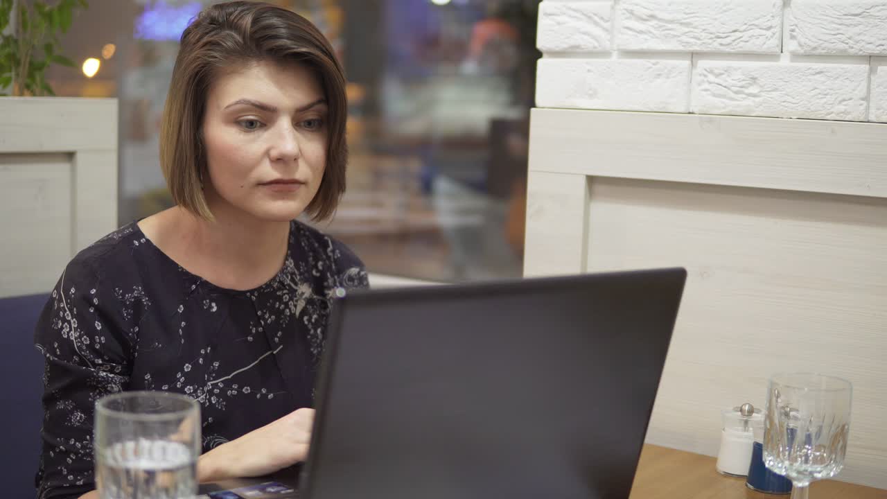 joven mujer de negocios sentada junto a la ventana con una computadora portátil y trabajando