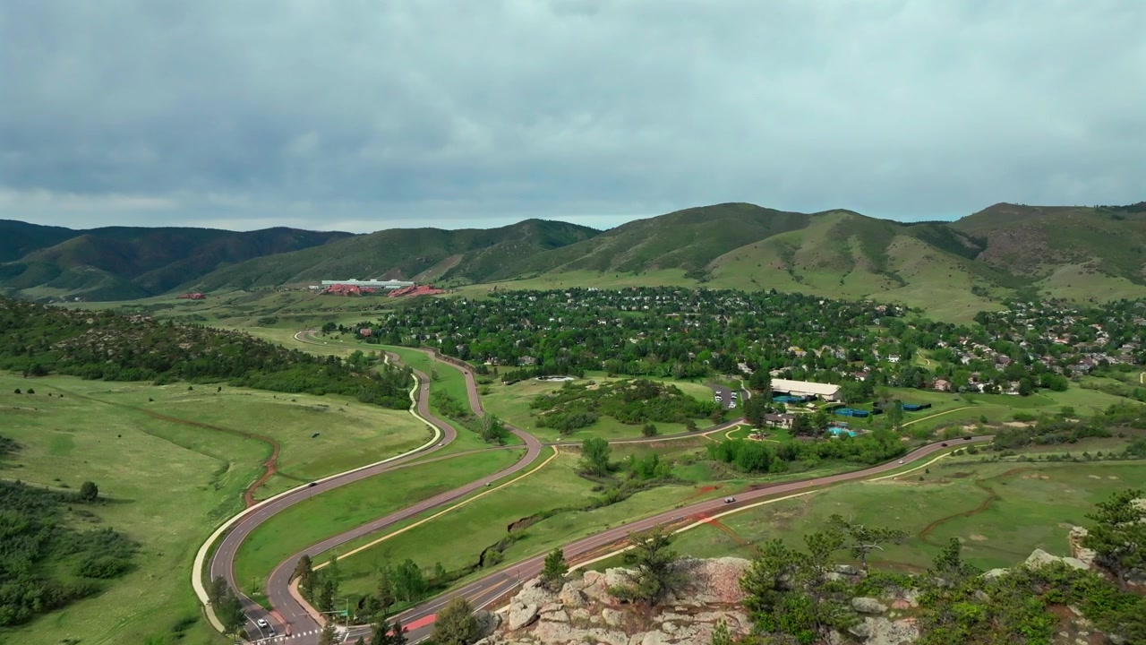 Vista aérea con dron de la entrada al sendero Meadow Ranch South Valley en Ken Caryl Valley Ranch, Cresta Hogback, Denver, Colorado, en una mañana soleada de verano con cielo azul, con un paneo hacia adelante y hacia arriba sobre las estribaciones de las Montañas Rocosas Front Range.