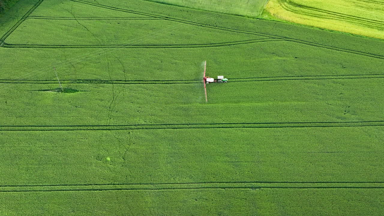 트랙 으로 초록색  을 스프레이 하는 작물 스프레이터 의 공중 사진