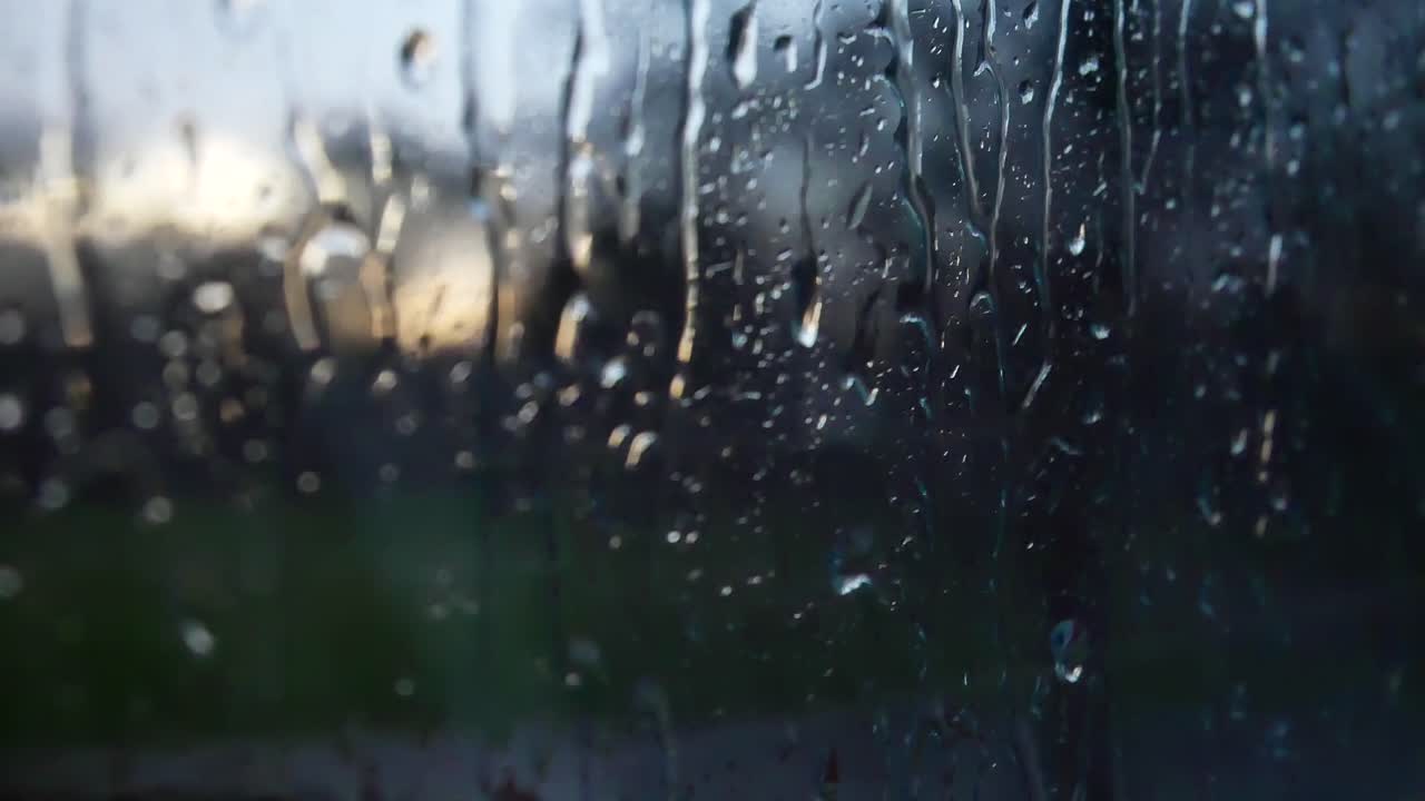 Rainy storm droplets, moody weather fall down window glass closeup bokeh