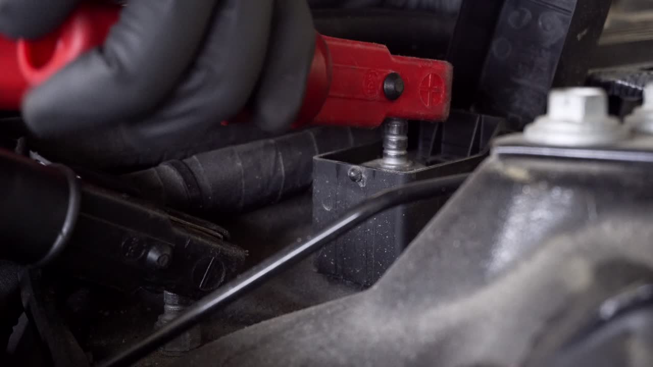 el mecánico de automóviles está conectando el cargador de batería con cables a puntos de carga especiales en el automóvil para la programación