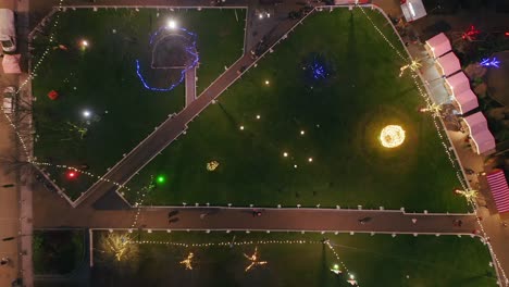 aerial top down ascend above christmas lights and festive market in eyre square galway, ireland, warmth of joyous season in the evening