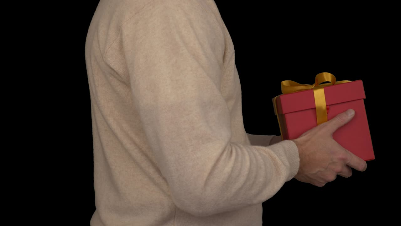 베이지 스웨터를 입은 코카시안 남자가 선물 상자를 손에 들고 있습니다. 캐주얼 베지 스웨터을 입은 남자의 측면 뷰. 남자는 선물을 줍니다. 알파 채널 크로마 키 투명한 배경. 잠겼습니다.