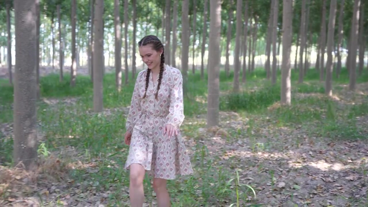 Una giovane donna che cammina con grazia attraverso una foresta serena, piena della bellezza della natura.