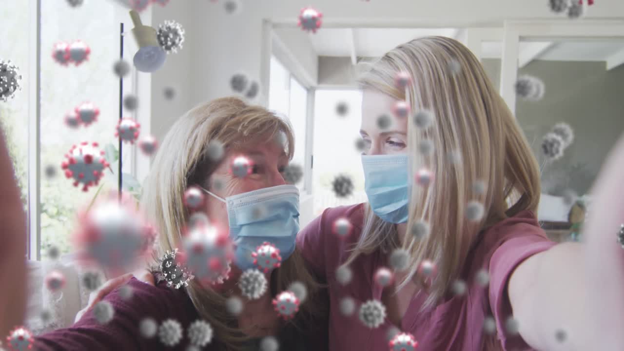 코로나19 세포에 대항하는 백인 어머니와 딸은 얼굴 마스크를 쓰고 집에서 웃고 있습니다.