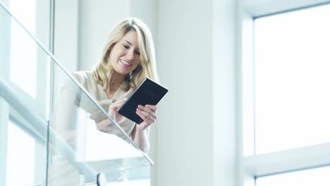 mujer de negocios rubia caucásica viendo noticias en un dispositivo de tableta