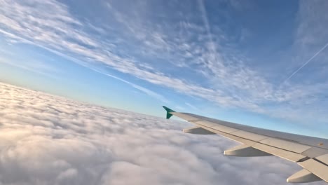 aircraft flying above cloudscape, side window view