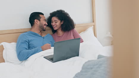 Couple-watching-a-movie-on-laptop-in-bed-laughing