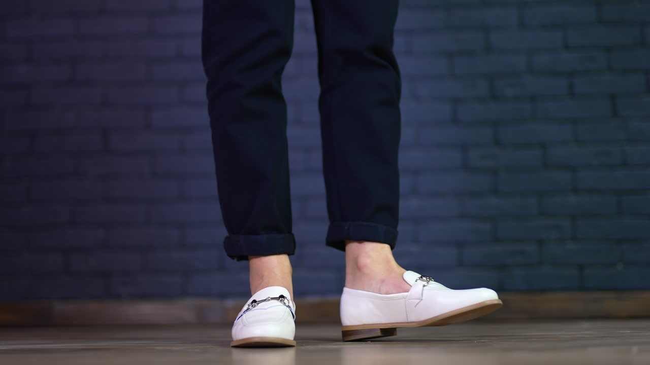 White shoes demonstration on a model. Female feet twisting back and forth in new comfortable footwear. Blue brick backdrop.