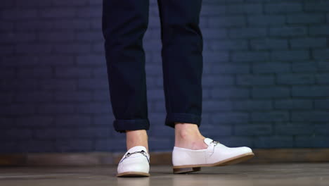 white shoes demonstration on a model. female feet twisting back and forth in new comfortable footwear. blue brick backdrop.