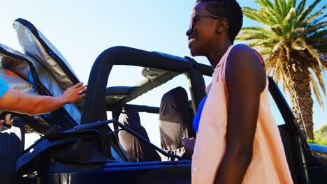 Group-of-female-friends-removing-surfboard-from-car-4k