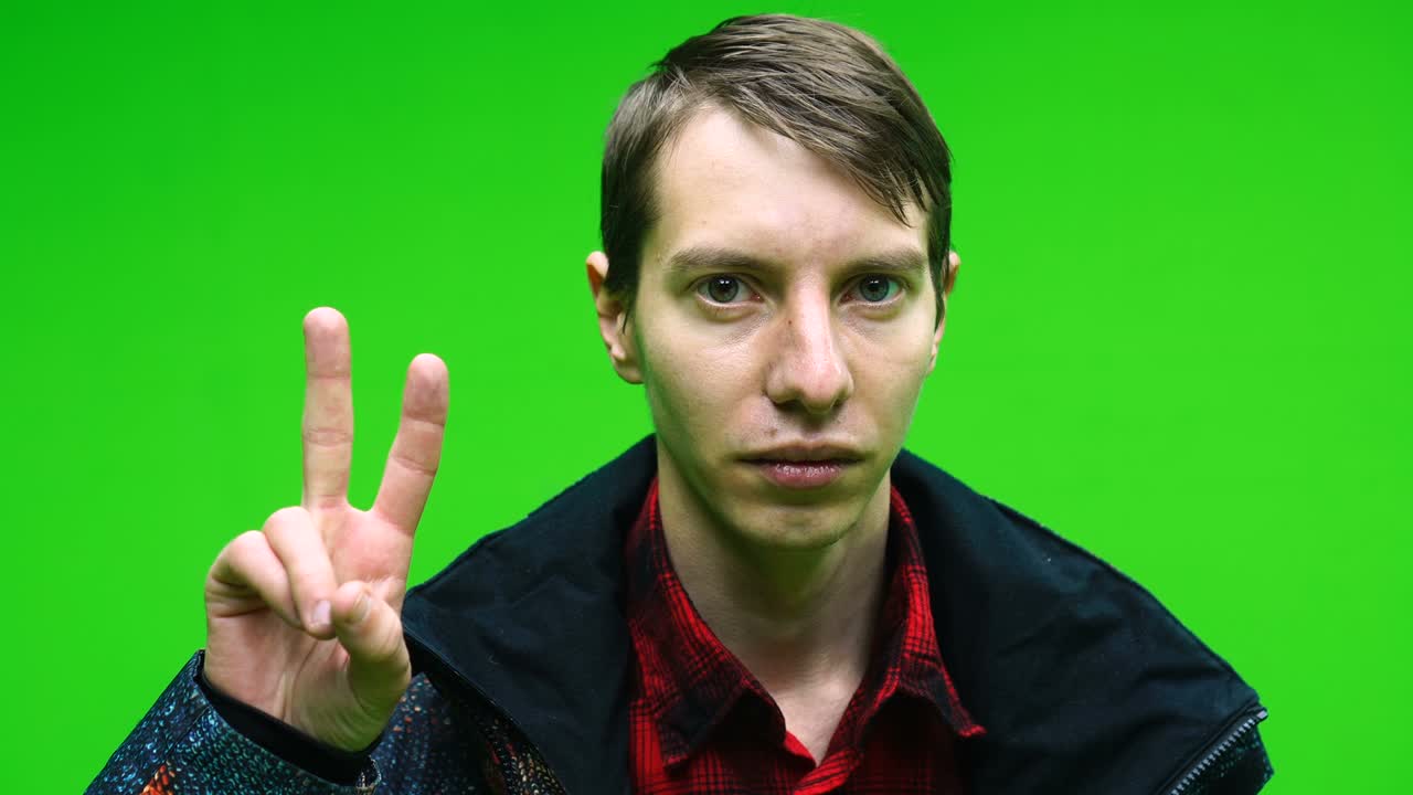 Young man in casual clothing showing victory sign hand on green screen background. Chroma key