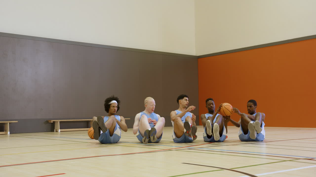 Basketball team doing core exercises in gym, focused on fitness training