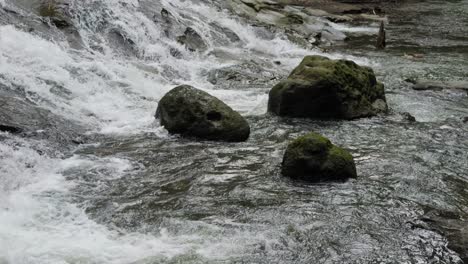 The-mesmerizing-Goa-Rang-Reng-waterfall-cascading-into-a-serene-river-on-the-island-of-Bali,-Indonesia