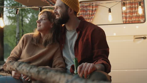 pareja feliz hablando junto a un fuego de campamento por la noche