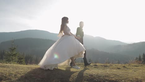 Recién-Casados.-Novio-Caucásico-Con-Novia-Corriendo-Por-La-Ladera-De-La-Montaña.-Pareja-De-Novios