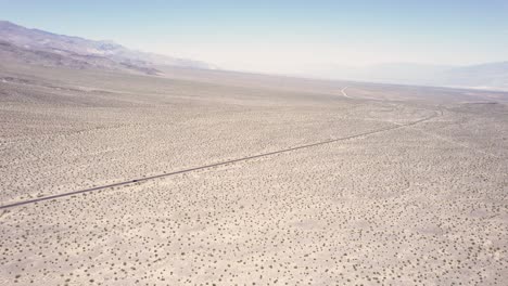 Drone-following-a-car-from-far-away-driving-in-a-desert-landscape-in-4k