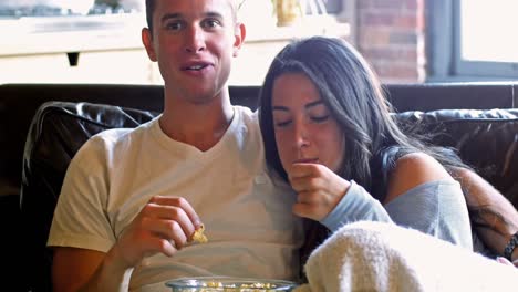 una pareja comiendo palomitas de maíz en la sala de estar.
