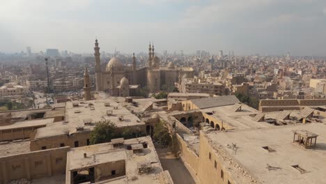vista panorámica inclinada hacia arriba del paisaje urbano y el horizonte de el cairo con la mezquita-madrasa del sultán hassan en el fondo, egipto