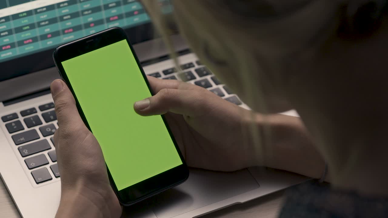 초록색 화면 을 가진 휴대 전화 를 들고 있는 손