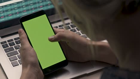 mano sosteniendo un teléfono móvil con pantalla verde