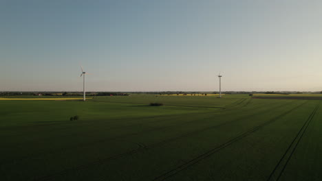 drone climbing in altitude over beautiful country field, electric windmills