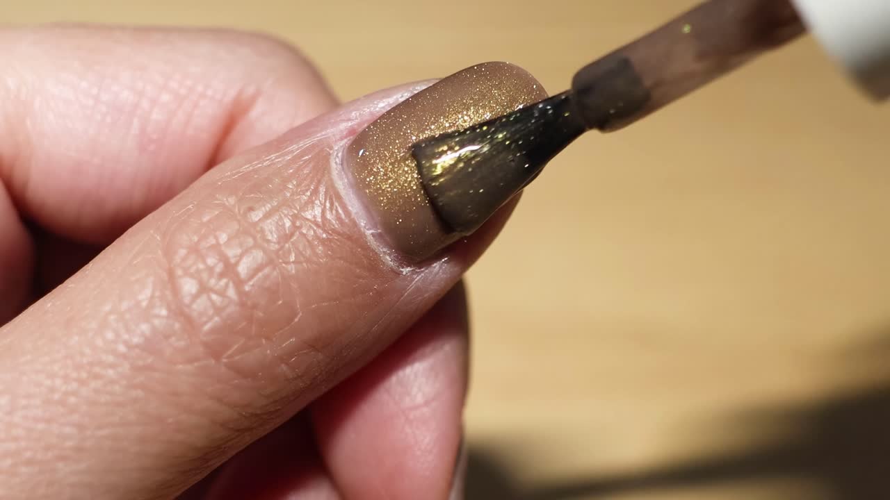 Applying Brown Nail Polish with Gold Glitter