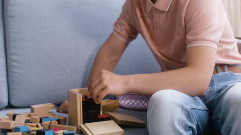 vista en primer plano de un niño con síndrome de down y su madre jugando con cubos de madera en el sofá de la sala de estar en casa