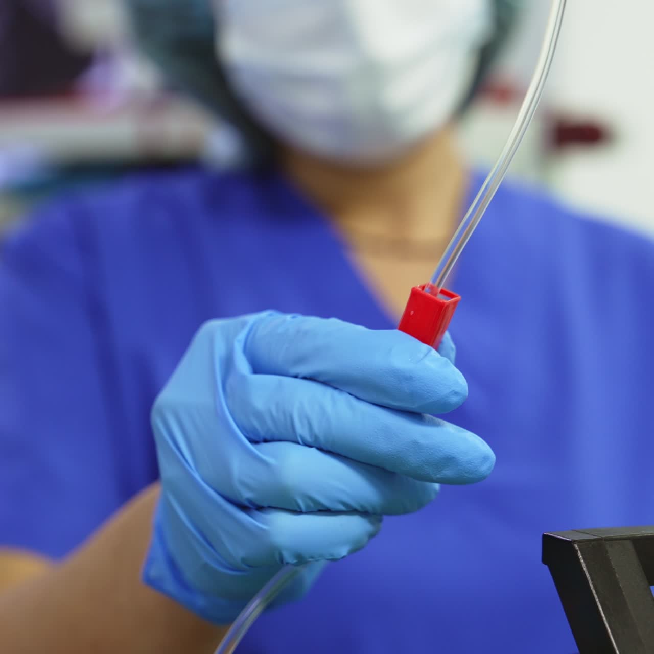 Surgeon assistant's hand installing the injection drip. Controlling medical equipment during operation close up. Blurred background