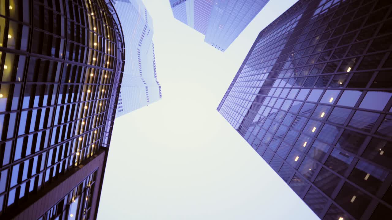 Looking up at skyscrapers downtown at dusk, clear sky and building lights with reflections