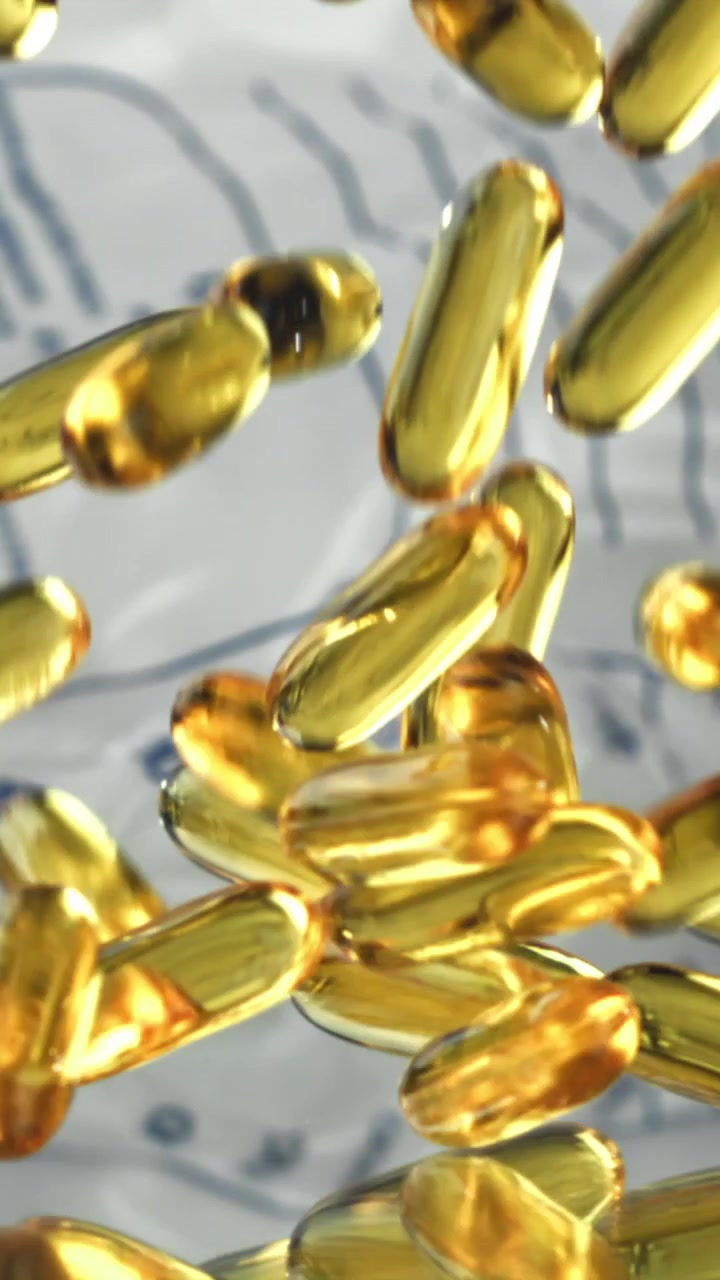 Capsule dorate di Omega-3 che cadono al rallentatore