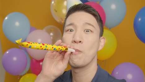 pov studio portrait of man taking selfie wearing party hat celebrating birthday surrounded by balloons 1