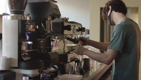 male barista making coffee using coffee machine